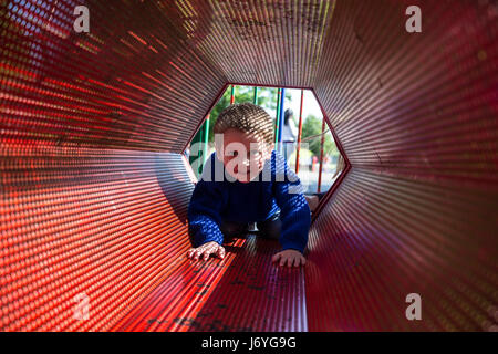 Enfant jouant dans l'équipement de jeu,rouge,nonage fou sport chiens s'ébattre joyeusement dans le champ jardin. revel trifle caper Les enfants ont été capering à propos, Banque D'Images