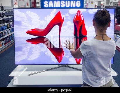 Woman looking at Samsung QLED TV en magasin électrique. Banque D'Images