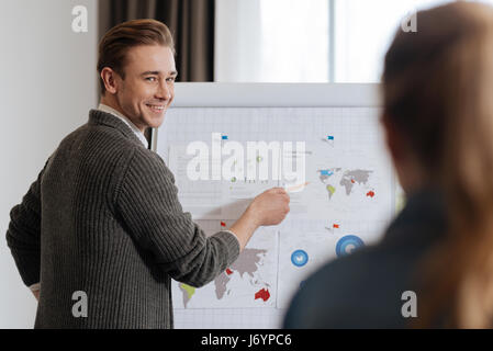 Homme heureux joyeux pointant sur la carte du monde Banque D'Images