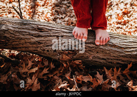 Close-up of boy standing on a log barefoot Banque D'Images