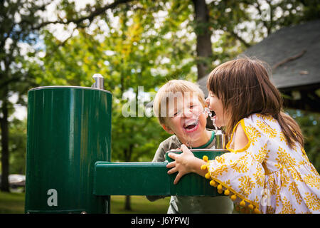 Deux enfants heureux buvant de l'eau d'une fontaine Banque D'Images