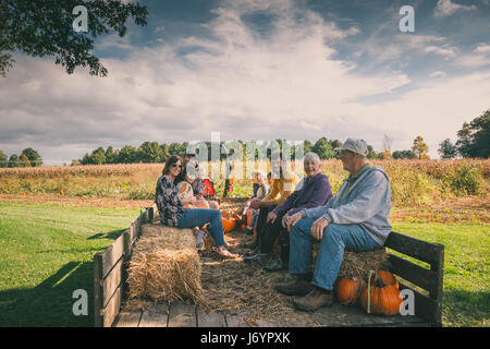 Multi-generation family sitting dans un chariot à une citrouille Banque D'Images