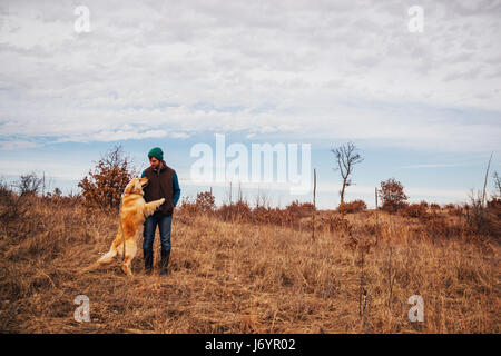 Homme debout dans un paysage rural avec golden retriever dog Banque D'Images