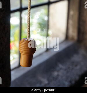 Bouton de poignée en bois ou sur une corde à tirer dans une vieille fenêtre en pierre Banque D'Images