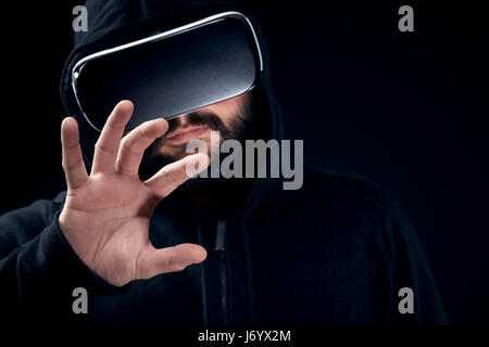 Jeune hipster barbu portant des lunettes de réalité virtuelle. fond noir studio concept vr Banque D'Images