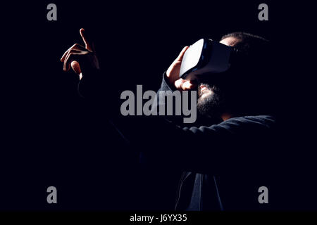 Jeune hipster barbu portant des lunettes de réalité virtuelle. fond noir studio concept vr Banque D'Images