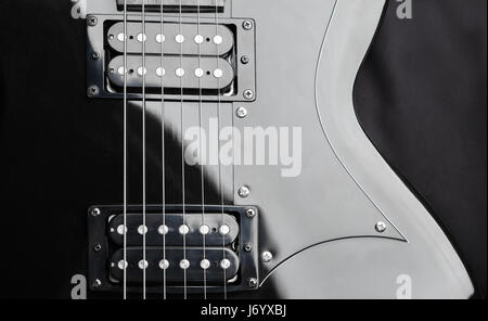 Un fragment d'une guitare à cordes en acier noir. Fond sombre. Banque D'Images