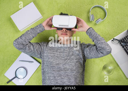 Top view of asian man wearing virtual reality goggles. Man lying on the floor. Banque D'Images