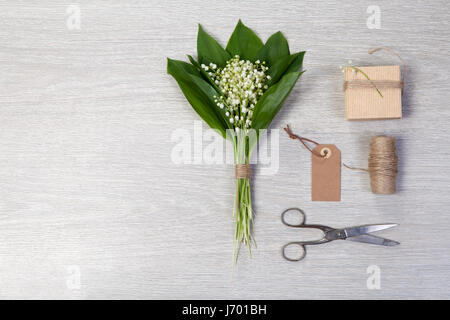 Lilly de la vallée des fleurs et des feuilles bouquet cadeau boîte sur fond de bois. Copy space Banque D'Images