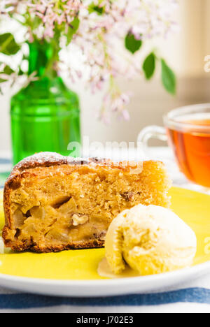 Tranche de gâteau pommes maison douce servi avec de la crème glacée et tasse de thé Banque D'Images