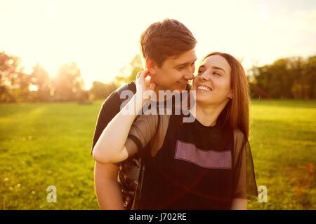 Un couple aimant câlins dans le parc au coucher du soleil. Banque D'Images