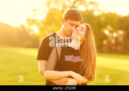 Un couple aimant câlins dans le parc au coucher du soleil Banque D'Images