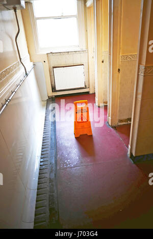 Prudence en plastique jaune signe sol humide dans les toilettes pour hommes d'avertir les utilisateurs d'un risque de glisser Banque D'Images