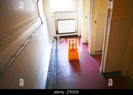 Prudence en plastique jaune signe sol humide dans les toilettes pour hommes d'avertir les utilisateurs d'un risque de glisser Banque D'Images