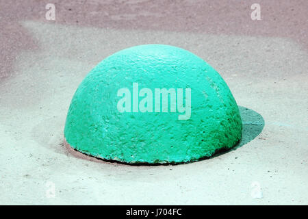 Des socles de béton en forme de boule à côté de la route à l'entrée des véhicules qui est mis en évidence par la réflexion de l'green windows d'un grand Banque D'Images