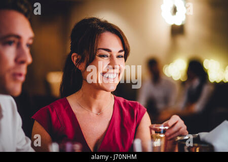 Close up of a young woman dans un restaurant. Elle déguste une coupe de champagne avec ses amis. Banque D'Images