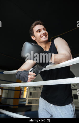 Smiling young boxer wearing boxing gloves and looking away Banque D'Images