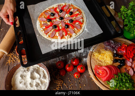 Matières pizza avec les ingrédients sur la plaque de cuisson Banque D'Images