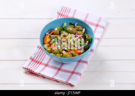 Bol de salade de légumes marinés avec olives vertes sur torchon à carreaux Banque D'Images