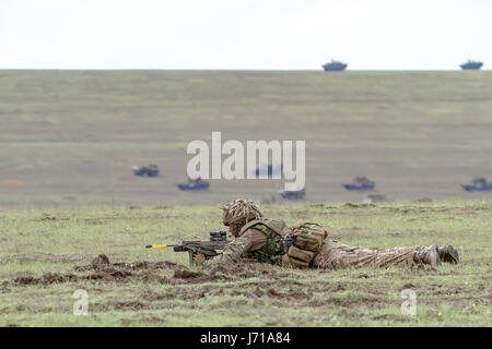 Les soldats britanniques courent pour une nouvelle position tout en étant défendus par des chars roumains et un hélicoptère d'attaque lors de l'exercice militaire de l'OTAN 'Wind Spring -15' au champ de tir de Smardan Banque D'Images