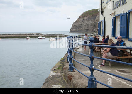 Staithes, UK. 22 mai, 2017. Météo britannique. Journée chaude mais ciel gris sur la mer à Staithes, un pittoresque village de pêcheurs dans le Nord du Yorkshire, UK. Les gens assis dehors le crabe et le homard pub sur le front, profitant du beau temps. David Dixon/Alamy Live News Banque D'Images