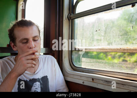 Une personne qui fume une cigarette dans un train à Cuba. Banque D'Images