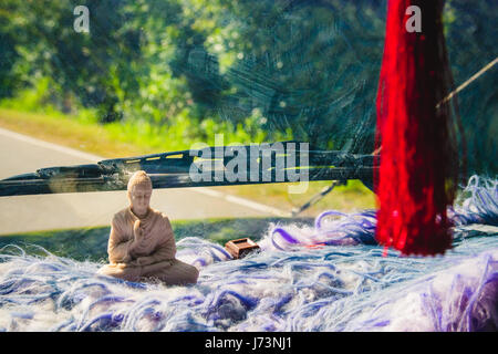 Une petite statue de Bouddha sur la planche de bord d'une voiture au Sri Lanka. Morceau de chocolat placées près de la statue comme une offrande. Banque D'Images