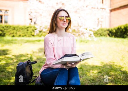 Contre l'arrière-plan de pré vert sam, jeune fille charmante - livre élève lit Banque D'Images