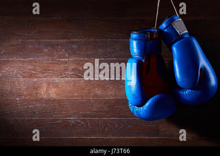 Une paire de gants de boxe rouge et bleu se bloque contre le fond de bois. Banque D'Images