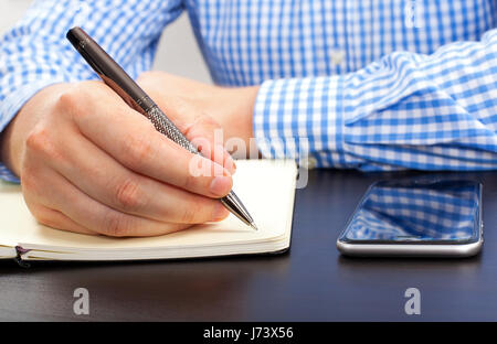 Businessman's hand writing notes tout en travaillant au bureau Banque D'Images