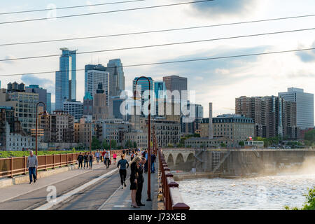 Les gens apprécient un sentier de randonnée pédestre et de vélo au Stone Arch Bridge de Minneapolis avec la ligne d'horizon à l'arrière-plan. Banque D'Images