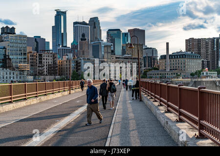 Les gens apprécient un sentier de randonnée pédestre et de vélo au Stone Arch Bridge de Minneapolis avec la ligne d'horizon à l'arrière-plan. Banque D'Images