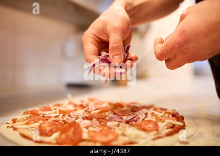 Ajouter l'oignon à cuire une pizza à la pizzeria salami Banque D'Images