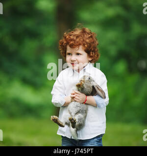 Petit garçon avec lapin sur l'herbe Banque D'Images