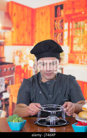 Beau jeune cheff de préparer un dîner gastronomique Suisse fondue sur table en bois en arrière-plan de cuisine Banque D'Images