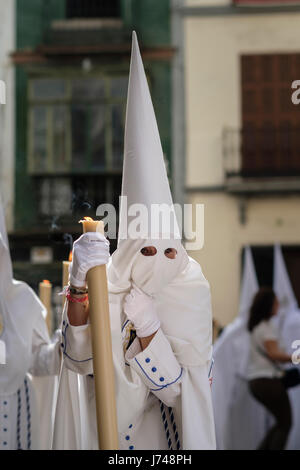 Nazarenos participant à une procession religieuse, avec les robes traditionnelles et capots et portant des bougies pendant la Semana Santa (Pâques) à Séville. Banque D'Images