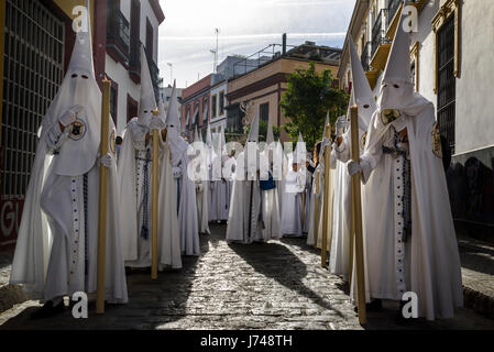 Nazarenos participant à une procession religieuse, avec les robes traditionnelles et capots et portant des bougies pendant la Semana Santa (Pâques) à Séville. Banque D'Images