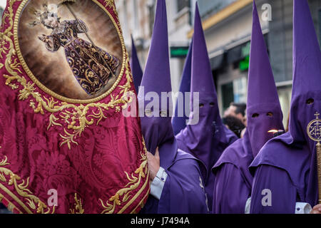 Nazarenos participant à une procession religieuse, avec les robes traditionnelles et capots et portant une banderole pour leur fraternité au cours de Semana Sant Banque D'Images