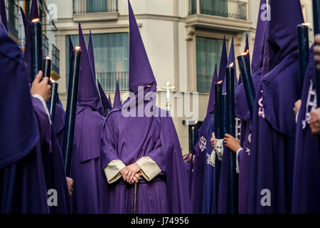 Nazarenos participant à une procession religieuse, avec les robes traditionnelles et capots et portant des bougies pendant la Semana Santa (Pâques) à Séville. Banque D'Images