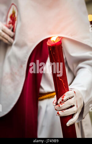 Nazarenos participant à une procession religieuse, avec les robes traditionnelles et capots et portant des bougies pendant la Semana Santa (Pâques) à Séville. Banque D'Images