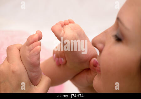 Maman embrasse les pieds d'un un-année-vieille fille. Banque D'Images