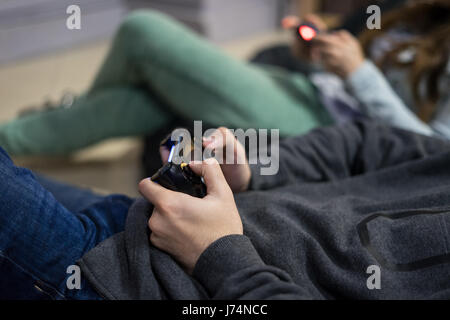 Couple heureux les amis à jouer aux jeux vidéo avec manette assis sur chaise de sac d'haricot Banque D'Images