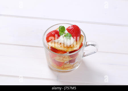 Tasse de yaourt blanc avec des crêpes américaines et de fraises fraîches sur fond de bois blanc Banque D'Images