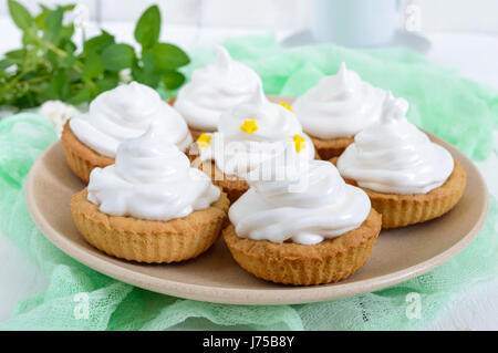 Mini tarte avec une crème d'air sur une assiette et une tasse de café sur un fond de bois blanc. Close up Banque D'Images