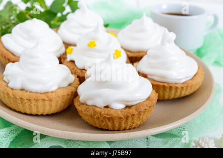 Mini tarte avec une crème d'air sur une assiette et une tasse de café sur un fond de bois blanc. Close up Banque D'Images