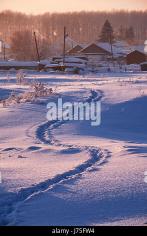 Sentier des traces dans la neige, dans l'Altaï russe village en hiver à l'heure du matin, Sibérie, Russie Banque D'Images