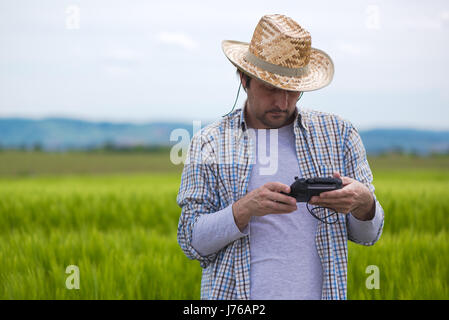 Concept d'agriculture intelligente, agriculteur à l'aide de la télécommande pour naviguer drone avion en champ cultivé et examiner les grandes cultures Banque D'Images