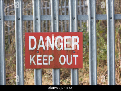 Signe danger Keep Out, lettres blanches sur fond rouge fixées à des clôtures en acier galvanisé dans whitefield lancashire royaume-uni Banque D'Images