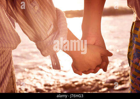 Jeune couple amoureux se tenant la main en regardant la marée basse à plage. Banque D'Images