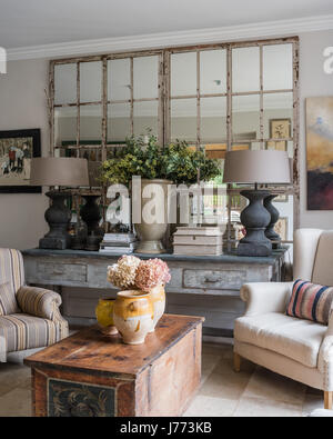 Paire de grandes lampes Tigné Tierlan gris sur de grandes table console en coin salon avec des fauteuils à dossier d'aile et commode ancienne. La peinture elle par sus Banque D'Images